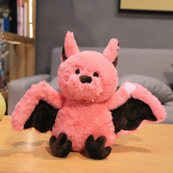 Soft bat plushie: A pink Soft bat plushie with outstretched wings is sitting on a table